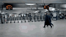 two men walk through a subway station with a sign that says no smoking on it