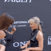 two women standing in front of a wall that says national