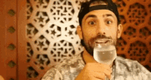 a man with a beard is holding a glass of water in his mouth .