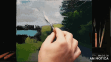 a hand is holding a spatula and painting on a canvas with the words made in animotica on the bottom