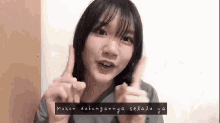 a young girl is giving a thumbs up sign while wearing a grey shirt .