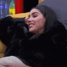 a woman in a fur coat is sitting on a couch eating popcorn