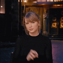 a woman in a black sweater is making a funny face