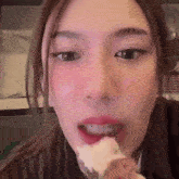 a close up of a woman 's face with a piece of food in her mouth