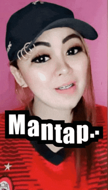 a woman wearing a hat and a red shirt with the word mantap written on it