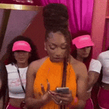 a woman wearing a pink visor looks at her phone