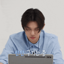 a man in a blue shirt is sitting in front of a laptop with chinese writing on it