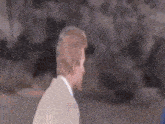 a man in a suit is standing next to a woman in a blue jacket and talking to her .