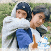 a man in a hoodie hugs another man in a blue shirt