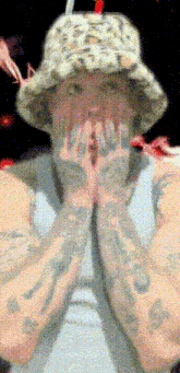 a man with tattoos on his arms wearing a bucket hat