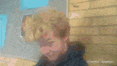 a man is making a funny face in front of a brick wall with a watermark that says hailuo ai on it