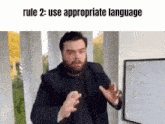 a man with a beard is standing in front of a white board with the words rule 2 : use appropriate language written on it