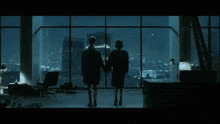 a man and a woman holding hands in front of a window
