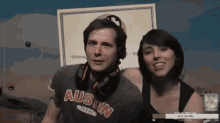 a man and a woman are posing for a picture and the man is wearing an austin shirt