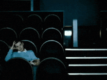 a man sits in a dark auditorium with his hand on his face