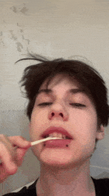 a young man brushing his teeth with a toothbrush
