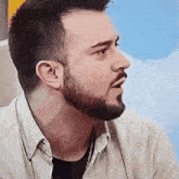 a man with a beard is wearing a white shirt and black shirt
