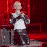 a woman is kneeling down on a stage with a microphone in her hand .
