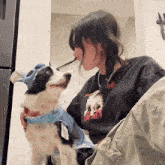 a woman holding a dog wearing a t-shirt that says ' stitch '