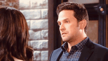 a man in a suit and plaid shirt looking at a woman
