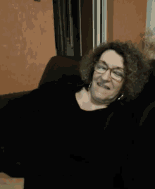 a woman with curly hair and glasses is smiling