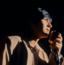 a man singing into a microphone with a shadow behind him