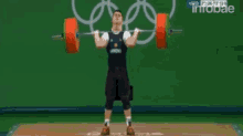 a man is lifting a barbell in front of an olympics logo