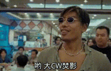 a man wearing sunglasses and a chain around his neck is standing in a crowded room with chinese writing on it