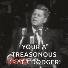 a man speaking into a microphone with the words " your a treasonous meatfat dodger "