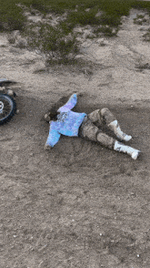 a person wearing a tie dye shirt is laying in the dirt
