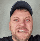 a man with a beard wearing a hat makes a funny face