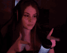 a woman wearing headphones and a necklace is giving a thumbs up sign