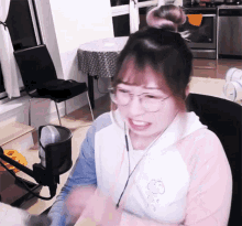a woman wearing glasses and headphones is sitting in front of a microphone in a room