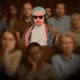 a man wearing a wig and sunglasses is sitting in a crowd