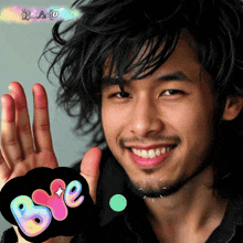 a man with a beard is smiling and holding up his hand next to a bye sign