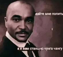 a man in a suit and tie with russian writing on the bottom right