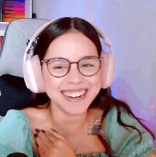 a woman wearing headphones and glasses is smiling and laughing .