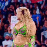 a woman in a green and purple outfit is standing in front of a crowd holding a sign that says ' i '