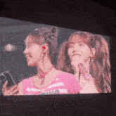 two girls are standing next to each other with one holding a phone and the other a microphone