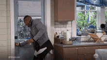 a man is standing in a kitchen holding a bottle of wine .