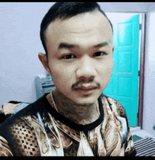 a man with a tattoo on his face is wearing a shirt with a snake print