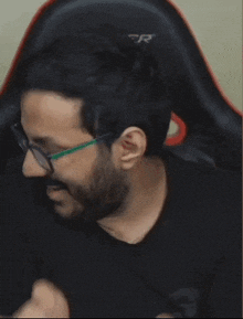 a man wearing glasses is sitting in a black cer chair