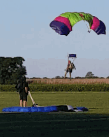 a person is standing in a field with a parachute flying overhead