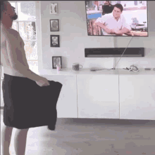 a shirtless man is standing in front of a flat screen television