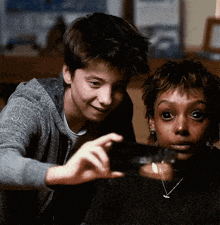 a boy and a girl are looking at a glass