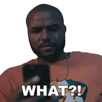 a man with a beard is looking at a cell phone and says what