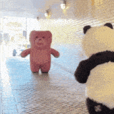 a pink teddy bear and a panda bear are standing next to each other