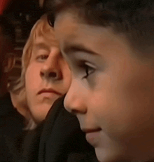 a close up of a young boy 's face with a man behind him .
