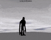 a silhouette of a man with very long arms stands in front of a cloudy sky ..