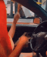 a woman with red hair is driving a toyota car and eating a sandwich